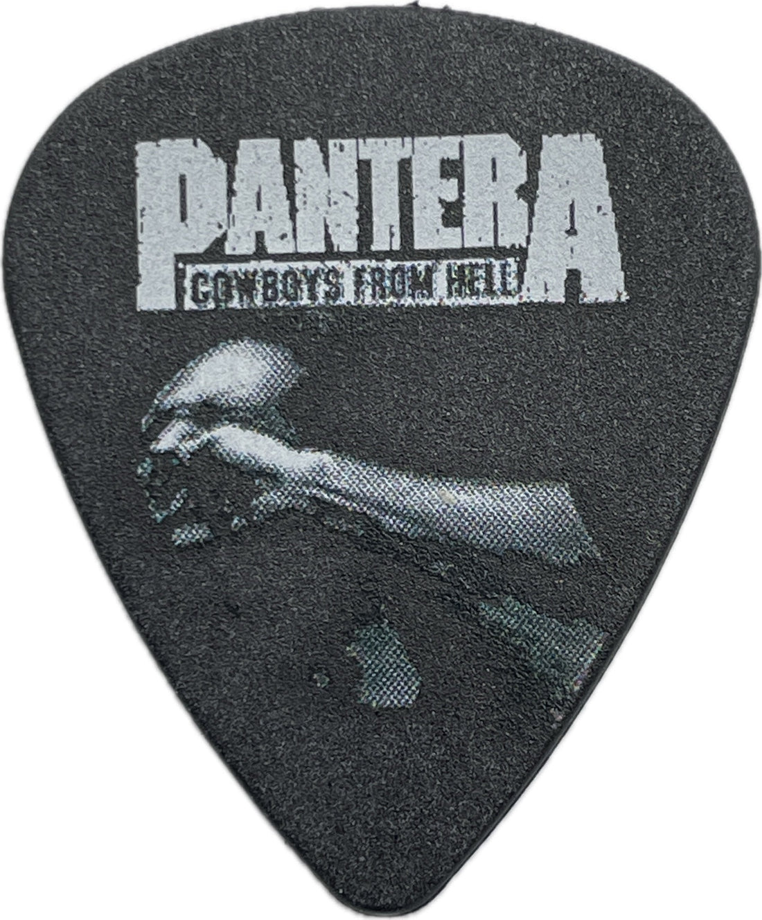 Front of a black Pantera guitar pick with Cowboys From Hell text and monochrome artwork